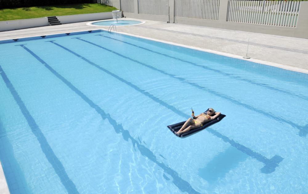 Woman relaxing in sun-heated pool representing solar pool heating benefits